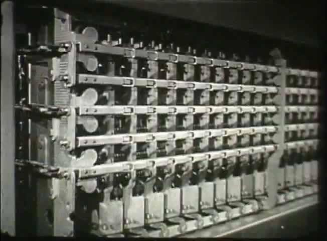 The still from 'Story Without End' features a detailed view of a mechanical switching system typical of the late 1940s. It showcases multiple rows of metallic levers and switches, indicative of the Bell System's telecommunication technology at the time. The machinery emphasizes the intricate design and functionality essential for the central office operations, reflecting the era's advancements in telephone network infrastructure.