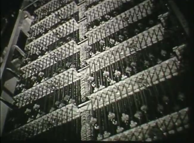 The still from 'Story Without End' showcases a close-up view of a central office switching system, likely reflecting the technology of the late 1940s. The image emphasizes the intricate arrangement of switching equipment, featuring rows of metallic components and wiring. This visual representation highlights the complexity and scale of the telecommunications network developed by the Bell System during that era. The focus on such infrastructure underlines the film's intent to inform viewers about the technological advancements and operational details of the telephone system at the time.