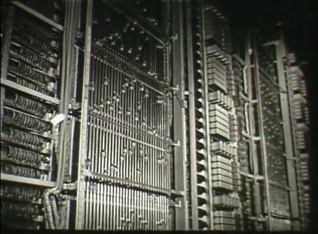 The still from *Story Without End* features intricate machinery, likely from a central telephone office. The image showcases rows of metallic components, including wiring and circuit boards, highlighting the technology used by the Bell System in the late 1940s. This visual emphasizes the complexity and scale of telecommunications infrastructure during that period.