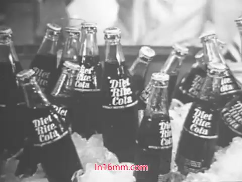 The 16mm still from the Diet Rite Cola commercial, featuring John 'Hondo' Havlicek, showcases a collection of Diet Rite Cola bottles arranged on ice. The bottles are labeled prominently, highlighting the product's branding. This commercial is set in the context of 1969, during a time when Diet Rite switched from cyclamate to saccharin as a sweetener. The imagery focuses on the beverage's refreshing appeal, fitting the promotional style of that era.