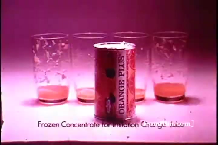 The still features a can of 'Orange Plus' frozen concentrate prominently in the foreground, surrounded by four empty glasses. The background has a pink hue, highlighting the orange juice residue at the bottom of the glasses. The text below reads, 'Frozen Concentrate for Imitation Orange Juice,' emphasizing the product's purpose. The vintage aesthetic reflects its 1970s origin.