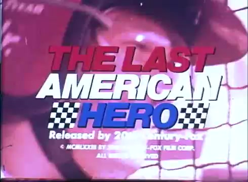 The still features the title 'THE LAST AMERICAN HERO' prominently displayed in bold red and blue letters, with a checkered pattern beneath it. The background appears to show a close-up of a race car driver's helmet, hinting at the film's focus on auto racing. The text notes the film's release by 20th Century Fox and includes a copyright symbol. The overall aesthetic reflects a vintage vibe typical of 16mm film trailers.