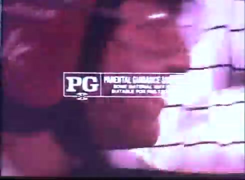 The still features a close-up of a character's face, possibly an intense moment in a racing context. The background is blurred, enhancing the focus on the character's expression. Overlayed is a 'PG' rating label, indicating parental guidance is suggested, along with a note that it is suitable for most viewers. The color palette appears warm, contributing to the nostalgic feel typical of classic trailers.