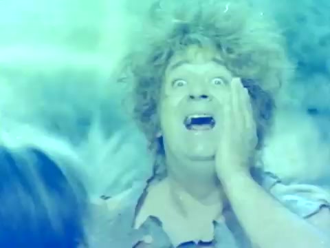 The still from the trailer of 'When Women Lost Their Tails' depicts a character with disheveled hair and an exaggerated facial expression, suggesting a comedic or absurd moment. The color palette features a blue tint, which adds a surreal quality to the image. This Italian film, originally released in 1970, likely employs humor to explore themes related to gender and societal norms, typical of its era. The provenance from Movielab indicates a focus on preserving this unique cinematic work for a potential rerelease.