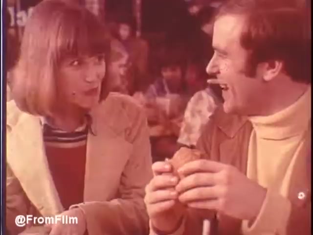 In this still from the 1976 McDonald's commercial, a young woman and man share a light-hearted moment in a restaurant. The woman, with short hair and a warm expression, looks at the man, who, smiling broadly, holds a burger in his hand. The relaxed, casual atmosphere reflects the vibrant dining culture of New Orleans. The colorful and vintage aesthetic captures the essence of McDonald's at that time. Would you eat at McDonald's in New Orleans? Maybe...   Follow us on Twitter @FromFilm.
