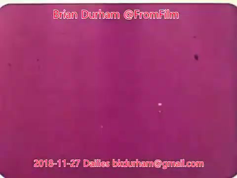 The 16mm still from '@FromFilm Dailies November 27, 2018' features a predominantly pink background with some visible specks or imperfections. It is a blank frame, possibly indicating a transition or test shot related to the film 'Dristan.' The text overlay includes the creator's name, email, and date, emphasizing a personal touch in the film dailies process.