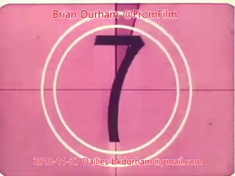 The still depicts a film countdown, showing the number '7' prominently in the center surrounded by two concentric circles. The background is a pinkish hue, typical of vintage film aesthetics. It appears to be part of the Dailies for November 27, 2018, from the '@FromFilm' collection.