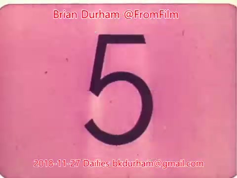 The still is a 16mm film frame featuring a large, bold number '5' against a pink background. The top and bottom edges show some grain and texture typical of film dailies. The frame includes credits attributed to Brian Durham, along with a date and contact information, indicating it is part of a series of film dailies from November 27, 2018.