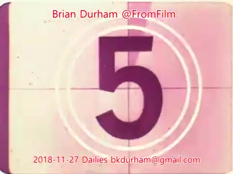 The still features a countdown from a vintage film projector, emphasizing the number '5' in the center within a circular frame. The background has a slightly faded look typical of 16mm film. The image includes text indicating the source, date, and contact information, suggesting it's part of a collection of film dailies. Overall, it conveys a nostalgic, classic film aesthetic.