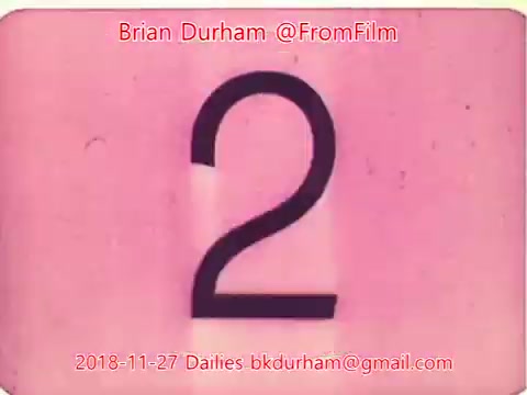 The still features a large, bold numeral '2' on a pink background, suggesting a film countdown or segment marker. The image is framed at the center with the date '2018-11-27' and the contact information for Brian Durham (@FromFilm) displayed at the top and bottom. The overall aesthetic reflects a vintage film presentation style.