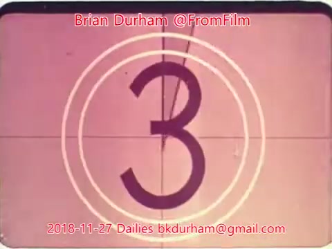 The image is a still from a 16mm film showing a classic countdown of '3' within a circular marking, indicating the final preparations for a scene to start. The background is a faded pink hue, typical of vintage film aesthetics. It includes the text 'Brian Durham @FromFilm' and a date, suggesting it’s part of a film project or dailies from November 27, 2018.