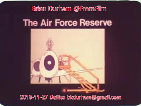 The still features a graphic representation related to 'The Air Force Reserve,' showcasing an image of an aircraft with a prominent target symbol and steps leading up to it. The background is simple, emphasizing the aircraft and the text. The image is tagged with credits to Brian Durham and the date, indicating it is from a set of film dailies.