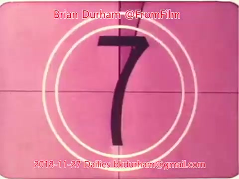 The image features a countdown, specifically the number '7,' displayed prominently against a pink background. The countdown is framed by circular markings typical of film projectors. The text includes a reference to Brian Durham and the date November 27, 2018, which suggests it is part of a film or video production's daily updates.