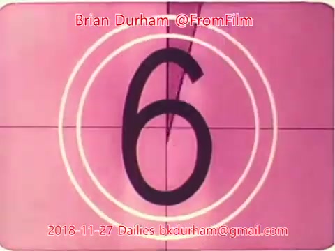 The still features a vintage film countdown showing the number '6' prominently in the center. It's set against a pink background with concentric circles, typical of old 16mm film countdowns. The date '2018-11-27' and contact information are also included at the bottom, indicating it's part of film dailies titled “ffn035-dristan-dailies” by Brian Durham.