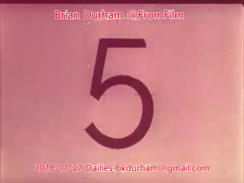The still features a large, bold number '5' on a soft, light-colored background. It appears to be a frame from a film dailies reel, indicating the countdown or cue for a scene. The text at the bottom identifies Brian Durham and includes a date and contact information. Overall, the image conveys a sense of classic filmmaking with a vintage aesthetic.