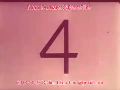 The still features a large, stylized numeral '4' on a soft pink background. The text at the bottom indicates it is from the 'From Film Dailies' dated November 27, 2018, attributed to Brian Durham, with contact details provided. The overall look suggests it is a frame from a film reel, possibly as part of a countdown or labeling sequence.