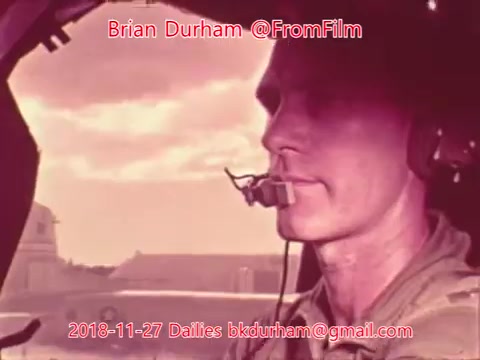 The still features a close-up of a focused pilot in the cockpit of an aircraft. The image has a vintage quality, likely from a 16mm film, with a soft color palette. The background shows hints of the aircraft and sky, giving a sense of atmosphere. Text overlays indicate the creator, Brian Durham, and additional details such as the date and email.