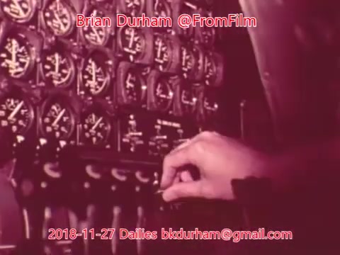 The 16mm still features a close-up of a hand adjusting controls on a panel filled with numerous gauges and dials. The image has a vintage quality, likely from an older film. The emphasis is on the mechanical aspect, suggesting a technical environment, possibly related to aviation or engineering. The background has a warm tone, and the overall feel is nostalgic.