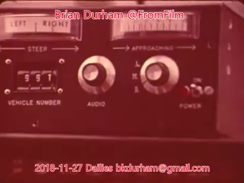 The still features a close-up of a vintage control panel, likely from a vehicle or film equipment. It includes dials labeled 'LEFT | RIGHT,' 'APPROACHING,' and 'POWER,' along with a display showing vehicle numbers and an 'AUDIO' dial. The overall design has a retro aesthetic characteristic of older technology. The image is marked with a watermark containing the name 'Brian Durham' and the date '2018-11-27.'