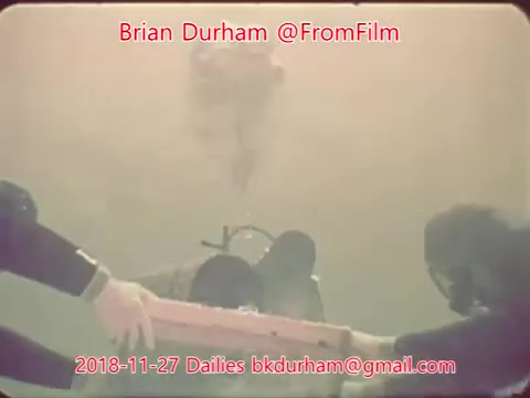The still depicts an underwater scene, possibly featuring divers, with a focus on a figure in the center who appears to be interacting with an object. There's a blurred background, creating a hazy, submerged atmosphere. The image is tinted, enhancing the underwater effect. Text overlays indicate it's from the Dailies of November 27, 2018, attributed to Brian Durham.