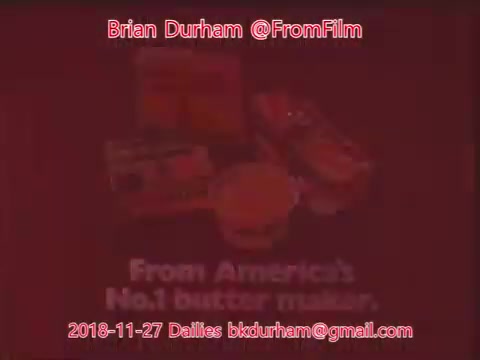 The still features a marketing graphic for a product, highlighting 'From America's No. 1 butter makers.' The background is reddish, and there's a display of various butter-related products, suggesting a promotional focus on a brand known for butter. The context indicates it's part of film dailies from November 27, 2018.