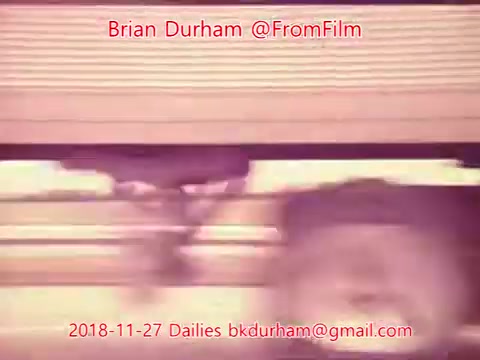 The still features a blurred motion effect, likely depicting a moving train or vehicle. The image has a soft, nostalgic quality, characterized by the 16mm film grain. Overlay text includes the name Brian Durham, the date November 27, 2018, and contact information. The composition emphasizes motion, creating a sense of speed and movement.