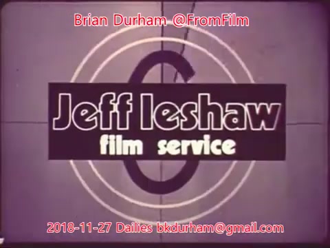The still features a stylized title card for 'Jeff Leshaw Film Service.' It displays bold, block letters with a circular design in the background, typical of mid-20th century film graphics. The date '2018-11-27' and contact information for Brian Durham are also included, indicating the image is a part of film dailies from that date. The overall aesthetic combines retro elements with a modern touch.