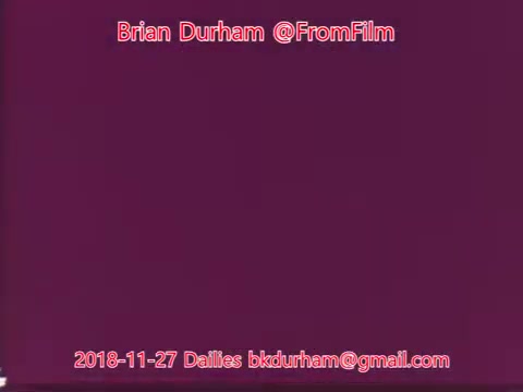 The still appears to feature a solid purple background with text overlay. The text includes the name 'Brian Durham' and the handle '@FromFilm,' along with the date '2018-11-27' and an email address for dailies. The overall composition is simple, focusing on the text against the colored backdrop.