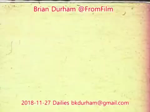 The still features a yellowish background with visible grain and slight texture, typical of 16mm film. It includes text overlayed in red, indicating the creator's name, username, and date of the dailies, implying a focus on film documentation or analysis. The overall aesthetic reflects a vintage film quality.