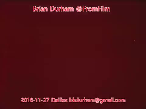 The still features a solid red background with text overlaying it. The text includes the name 'Brian Durham' and the handle '@FromFilm,' along with a date, '2018-11-27,' and an email. The overall aesthetic is minimalistic, highlighting the content in a straightforward manner.