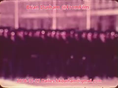 The still features a group of people arranged in a formation, likely dressed in uniforms. The image has a vintage look, evident from the color tone and slightly blurred quality, suggesting it’s taken from an older film reel. The context indicates it is part of a series of film dailies from November 27, 2018, associated with the user @FromFilm.