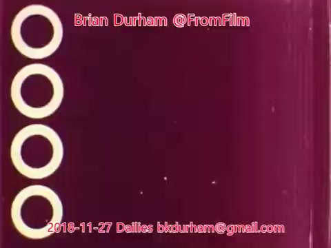 The still shows a maroon background with four white circular shapes aligned vertically on the left side. The image includes a watermark with the text 'Brian Durham @FromFilm' and an email address, along with the date '2018-11-27 Dailies.' The design is simple and focuses on the circular forms against a solid color.