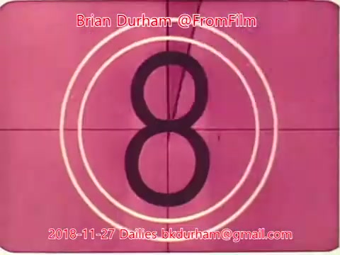 The image depicts a vintage-style countdown from a film projector, showing the number '8' prominently in the center. The background is a soft pink hue, surrounded by concentric white circles. The frame includes credit to Brian Durham and the date '2018-11-27' with a contact email related to film dailies. This style evokes nostalgia for classic filmmaking techniques.