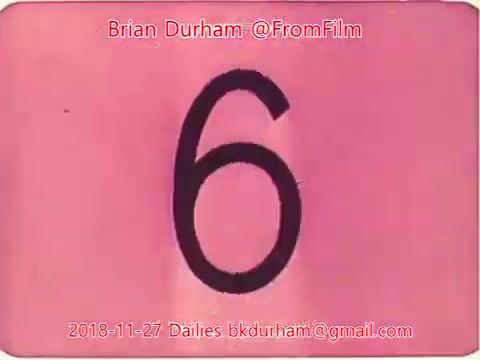 The still features a large black numeral '6' on a pinkish background. It includes the text 'Brian Durham @FromFilm' along with a date and email address, suggesting it is part of film dailies from November 27, 2018. The design appears vintage, typical of 16mm film stills.