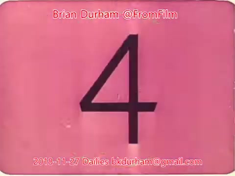 The still features a pink background with a large black number '4' prominently displayed in the center. It includes text indicating the creator, Brian Durham, and the date, November 27, 2018, along with contact information. The overall aesthetic appears to be typical of film dailies, suggesting it's part of a film production process.