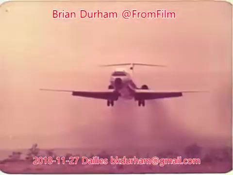 The still features an airplane approaching for landing, showcasing a hazy, atmospheric backdrop with soft colors. The image captures a moment in time, likely related to film dailies from November 27, 2018, suggesting a focus on aviation or transportation themes. The text overlay includes the name Brian Durham and contact information.