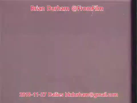 The still features a simple, muted background with soft, blurred colors. Text overlays identify the creator, Brian Durham, along with the date and an email address. The overall aesthetic suggests it is part of a film project or daily footage. The composition emphasizes the text more than specific visual imagery.