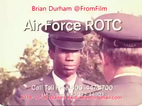 The still depicts a young man in an Air Force ROTC uniform, engaged in conversation with another individual, presumably an officer, who is partly out of view. The background suggests an outdoor setting, with greenery visible. The image is tinted, likely due to the film's age and characteristics of 16mm film. Text overlay includes contact information and credits the source as Brian Durham from '@FromFilm'.