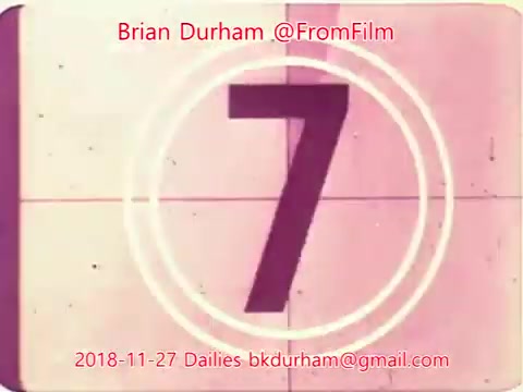 The still features a countdown timer displaying the number '7' against a vintage film background. The frame has a retro aesthetic, with a circular border and a faded color palette. Text overlays indicate the name Brian Durham, the date (November 27, 2018), and contact information. The style reflects classic film dailies, capturing a nostalgic feel.