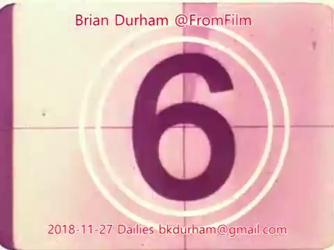 The still features a vintage-style film countdown, prominently displaying the number '6.' The design includes concentric circles typical of film projectors, set against a muted backdrop that implies an old film aesthetic. The date, '2018-11-27,' and the handle '@FromFilm' along with contact information are overlaid, indicating it's from a series of dailies by Brian Durham related to a project titled 'ffn035-dristan.'