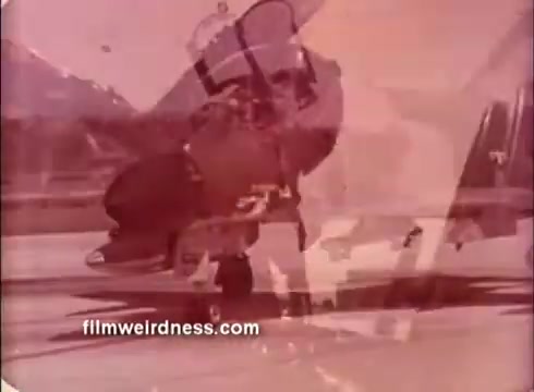 The still from the 1970s Air Force PSA features a jet aircraft in motion, possibly preparing for takeoff or landing. The image has a vintage look, characteristic of 16mm film, with a slightly faded quality. The backdrop may include an airbase or runway, adding to the military aviation context. Overall, it conveys a sense of action and patriotism typical of public service announcements from that era.