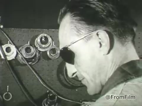 The still from 'American Foundation For The Blind PSA - 1968' features a person wearing sunglasses, seemingly focused on an array of tools or technical equipment in the background. The setting appears to highlight a workshop or a space related to technology, reflecting the AFB's mission to promote independence for people with vision loss through access to resources and tools. The image serves as a representation of empowerment and capability among individuals with visual impairments.