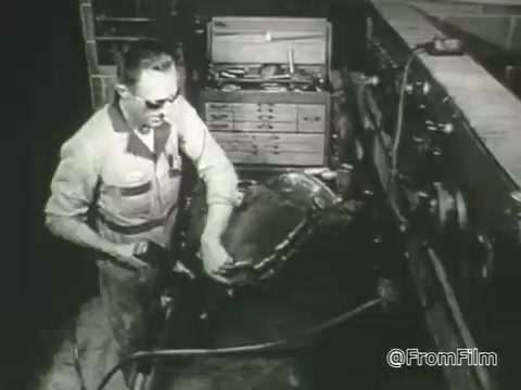 The still from the 1968 PSA by the American Foundation for the Blind features a man wearing sunglasses, engaged in a task that involves machinery or tools. He appears focused on his work in a dated workshop setting, emphasizing independence and capability despite vision loss. The image promotes the message of empowerment for individuals with vision impairment, highlighting their skills and contributions to society.