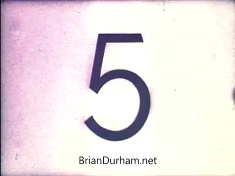 The still features a large, bold numeral '5' set against a light background, likely part of a countdown or sequence. The overall aesthetic suggests a vintage style, typical of film from the early 1970s. The simplicity of the design focuses attention on the number itself, indicative of its use in a promotional or instructional context related to the 'Lazy Dazy' doll from Ideal.