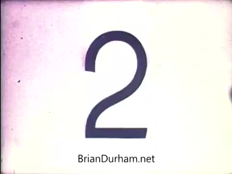 The still features a bold, stylized number '2' displayed against a muted, possibly faded background. The number has a distinct, vintage aesthetic typical of early 1970s film. The text 'BrianDurham.net' is prominently shown at the bottom, indicating a source or watermark. This still likely serves as part of a sequence related to the 'Lazy Dazy' doll from Ideal.