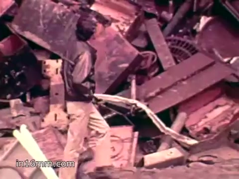 The still from 'Pat Paulsen PSA for the Environment Protection Agency - 1970s' depicts a person walking through a chaotic landscape of discarded materials, including metal and plastic debris. The scene highlights the significant volume of waste produced in the U.S., such as cans, bottles, and appliances, emphasizing the environmental impact of consumer throwaway culture. The voiceover underscores the staggering annual totals of solid waste, lending a sense of urgency to the need for environmental protection and waste management.