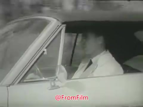 The still shows a close-up of a male driver in a classic car, likely from the 1960s. He appears focused and serious as he drives. The background is blurred, suggesting motion, which emphasizes themes of speeding and dangerous driving. The context is part of a public safety message by Aetna, aiming to raise awareness about the risks associated with reckless driving behaviors.