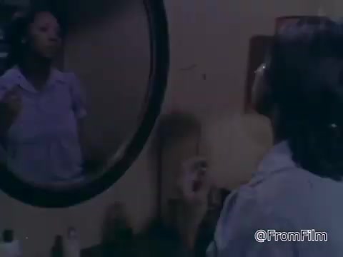 The still features a young woman standing in front of a round mirror, seemingly applying makeup or grooming herself. The setting conveys a personal, intimate atmosphere, likely emphasizing themes of self-care or confidence. The visual style reflects the era of the 1970s, characteristic of public service announcements aimed at raising awareness for the March of Dimes.