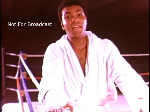 The still features Muhammad Ali in a boxing ring, wearing a white robe. He appears determined and engaged, likely addressing the camera with an inspirational or informative message regarding multiple sclerosis. The ring's ropes and background suggest an athletic setting, emphasizing Ali's status as a champion both in and out of the ring. The text indicating 'Not For Broadcast' suggests that this is a behind-the-scenes or unreleased footage.