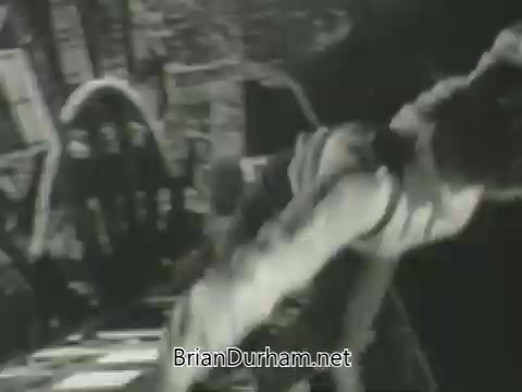 The still features a dramatic scene, likely from a television promo. A figure is engaged in an intense action, set against a backdrop that suggests a theatrical or surreal atmosphere. The black-and-white aesthetic emphasizes the energy and movement, indicative of the style typical of early 1960s promotions.